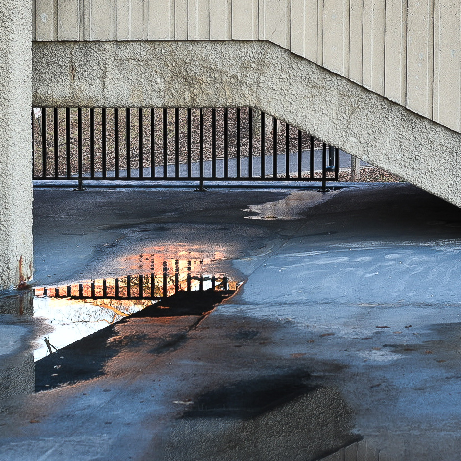 Water puddle reflecting sunlight under Concrete staircase
